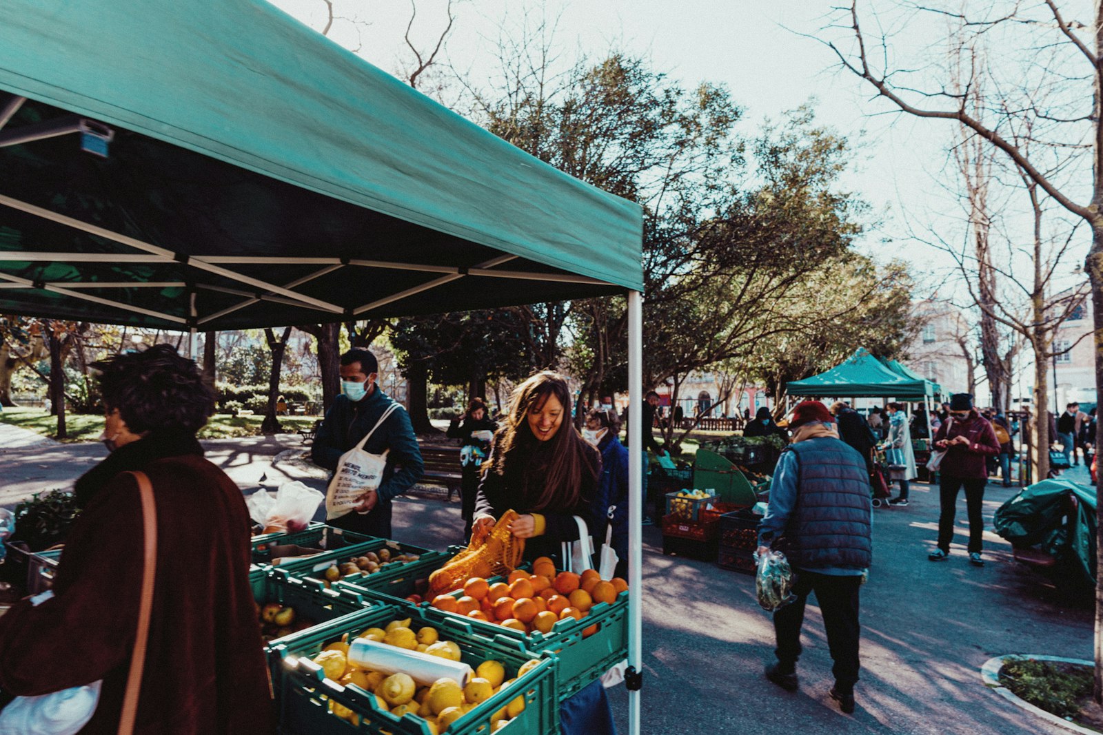 Mujer sonriendo mientras compra naranjas frescas en el mercado